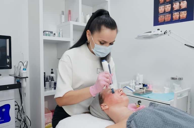 Aesthetician applying facial treatment with handheld device in modern spa clinic