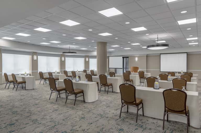 Modern conference room with white tables, brown chairs, and large windows with frosted glass panels
