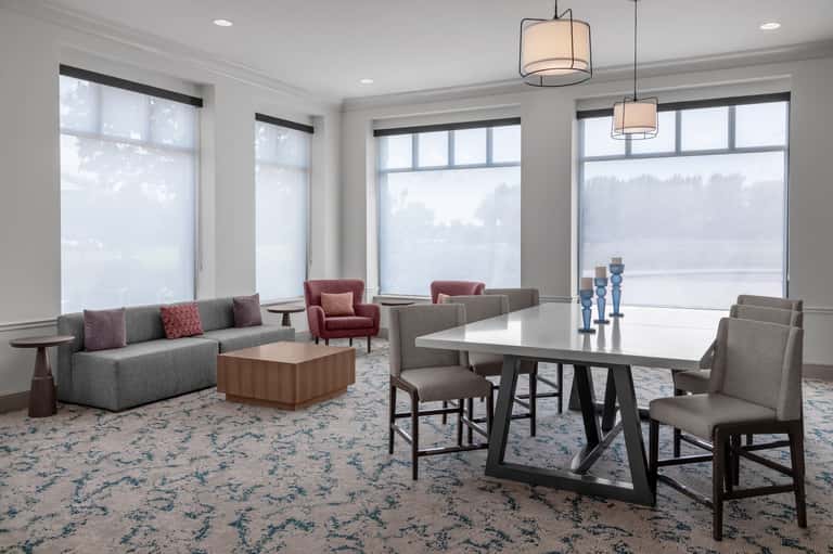 Spacious lounge with floor-to-ceiling windows, modern dining table, sofa, and pendant lighting