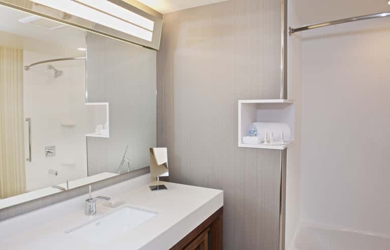 Modern bathroom with white vanity, large mirror, white subway tile walls, walk-in shower, and built-in shelving