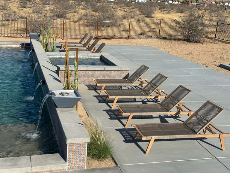 Luxury poolside lounge chairs with water feature and desert landscape views