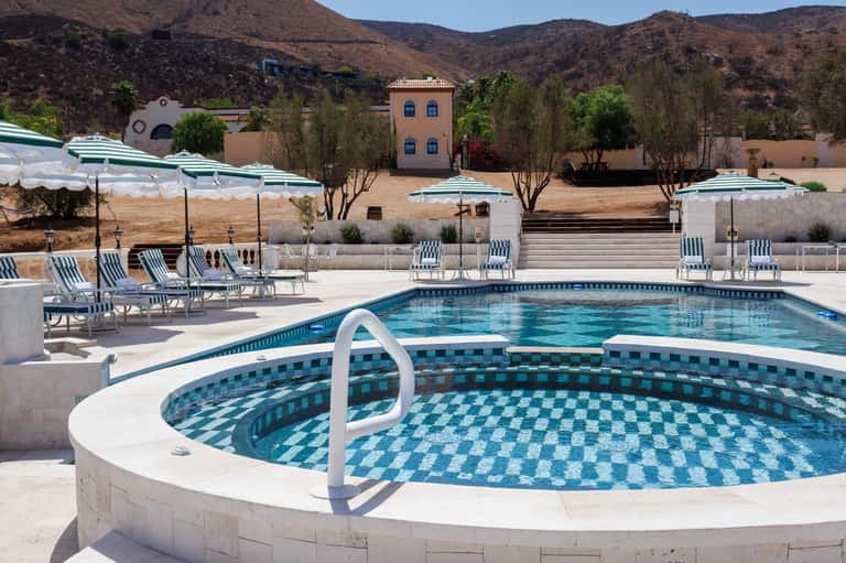 Resort pools and spa area with loungers, umbrellas, and desert mountain landscape