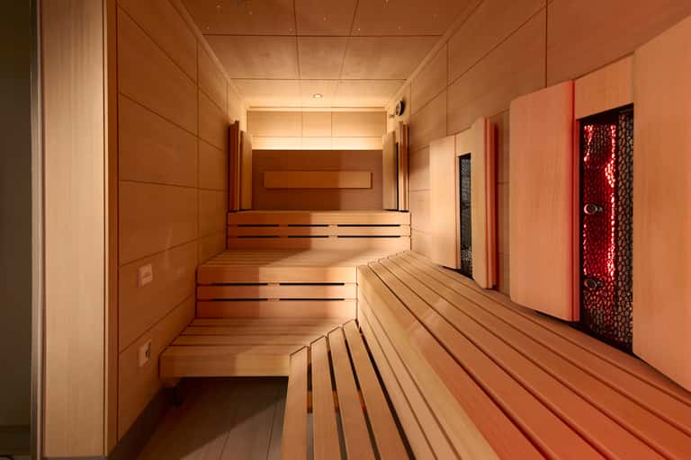 Modern spa sauna corridor with light wood paneling and red accent door