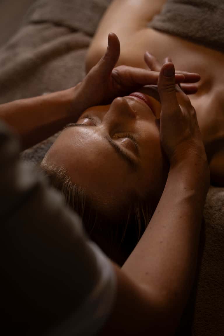 Close-up of relaxing spa facial massage treatment on client's face