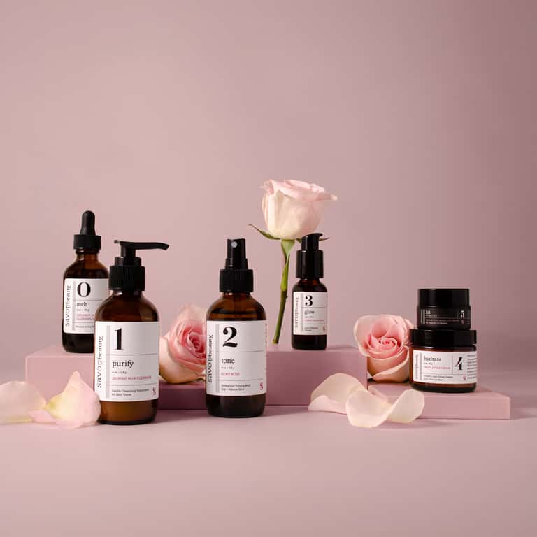 Savor Beauty five-step skincare product line with amber bottles and pink roses
