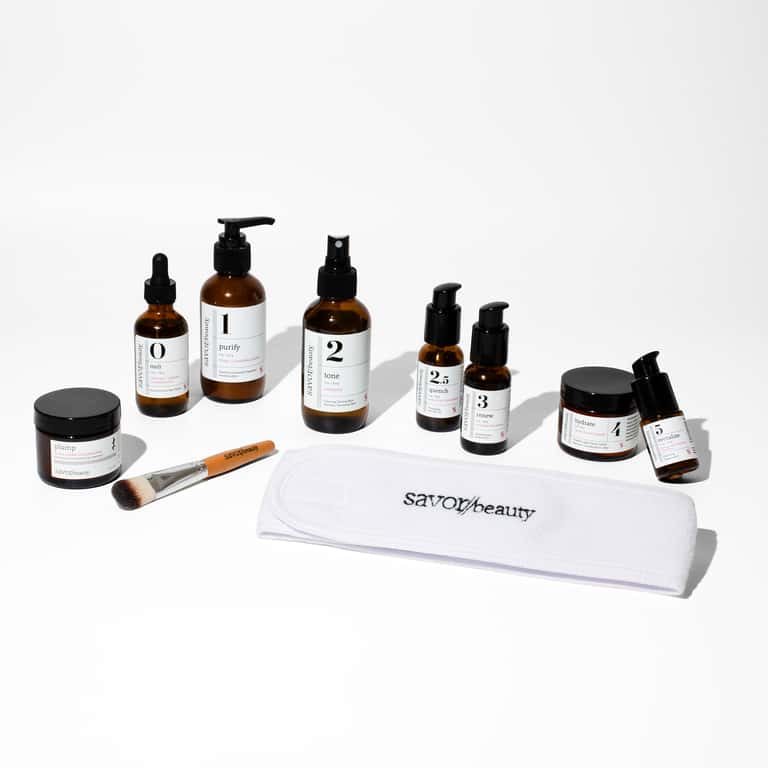 Complete Savor Beauty skincare kit with numbered products, brush, and white towel