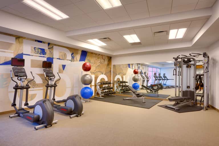 Modern hotel fitness center with cardio equipment, dumbbells, and exercise balls