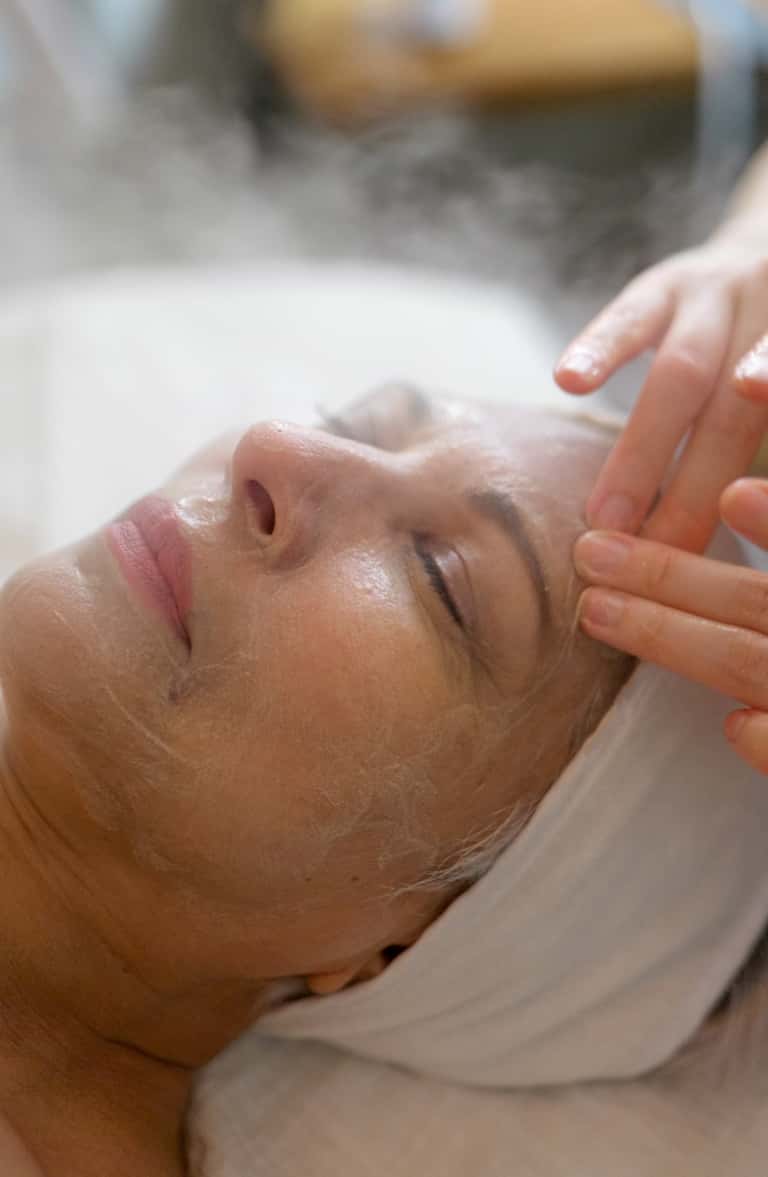Esthetician applying facial treatment to client's face during spa service