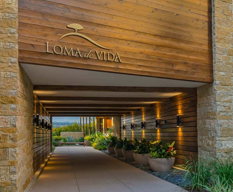 Loma de Vida spa entrance with wooden signage, stone pillars, and landscaped pathway
