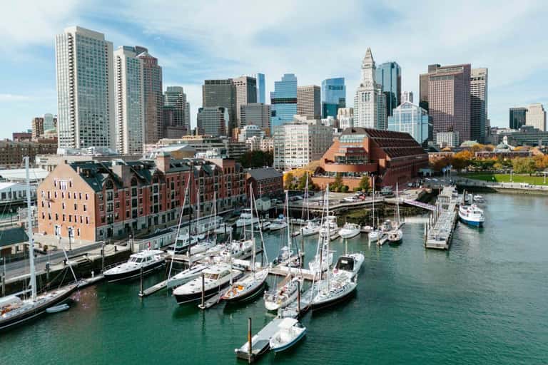 Boston waterfront skyline with sailboats docked at harbor and brick buildings in foreground