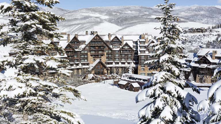 Snow-covered luxury mountain resort with alpine lodge architecture and ski slopes