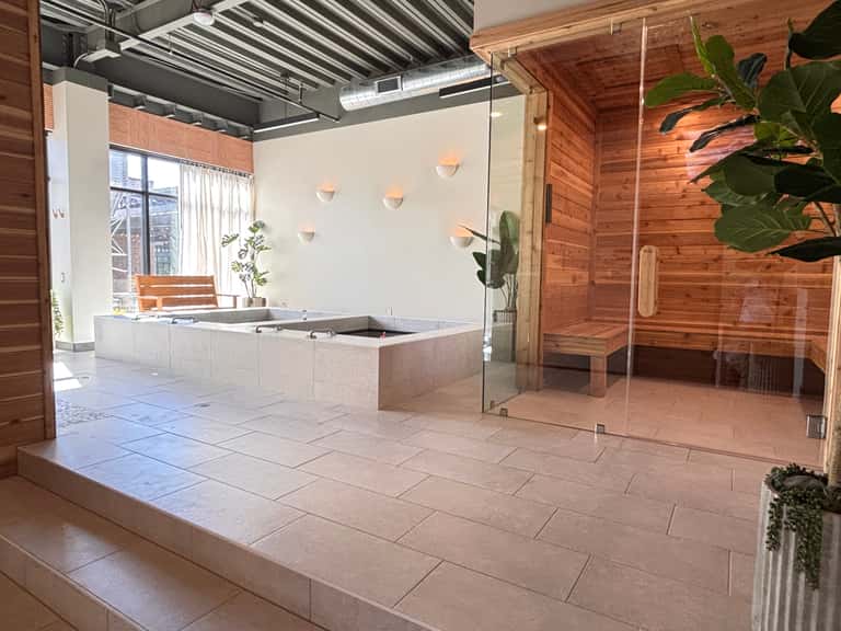 Spa facility with sunken hot tub, wooden sauna, and glass shower enclosure surrounded by plants