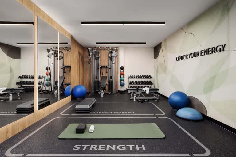Modern gym interior with cardio equipment, free weights, and motivational wall text