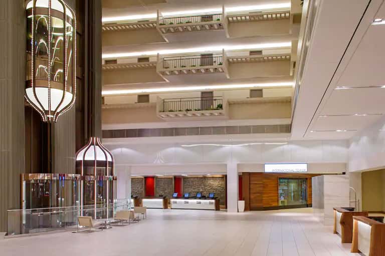 Modern hotel lobby with multi-level balconies, ornate chandelier, and marble floors