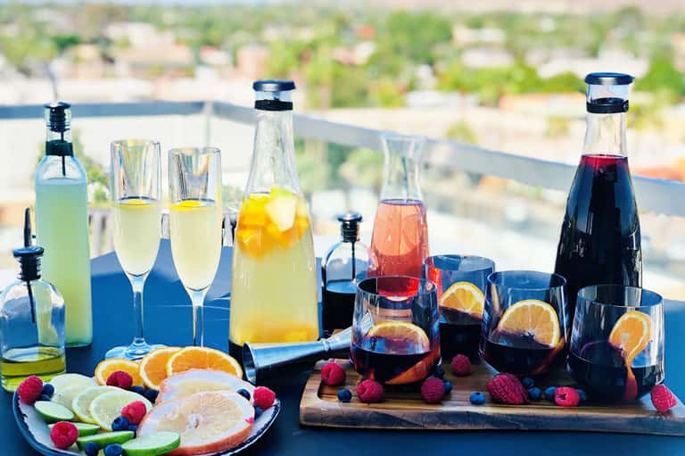 Colorful cocktails and mocktails with fresh fruits on rooftop overlooking cityscape