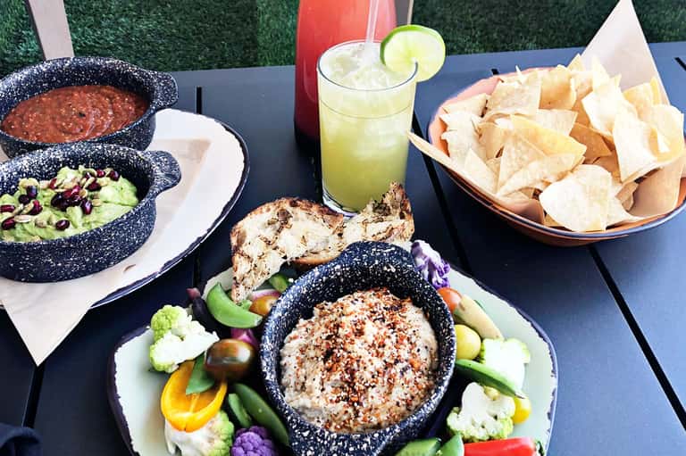 Poolside Mexican food spread with guacamole, salsa, chips, and margarita cocktail