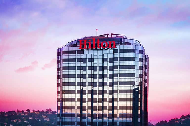 Hilton hotel building at dusk with pink and purple sky