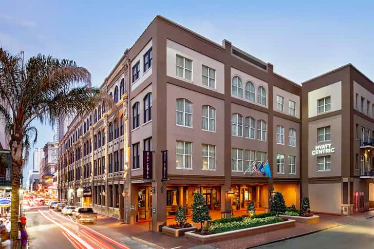Historic downtown building facade with brown and cream exterior, storefront windows, and palm trees
