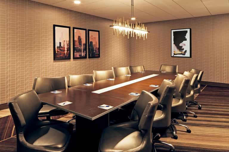 Modern conference room with long wooden table, leather chairs, and city skyline artwork
