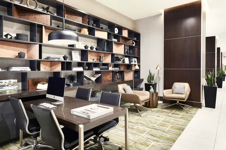 Modern executive office with floor-to-ceiling shelving, dark desk, and comfortable seating area