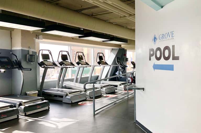 Fitness center with treadmills and exercise equipment in a bright, windowed gym space