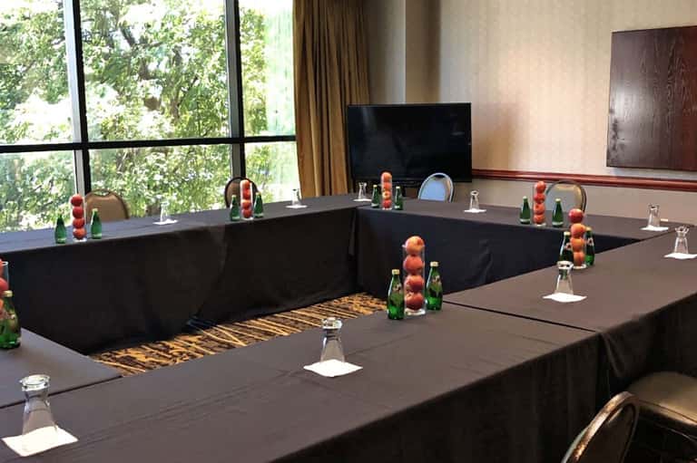 Conference room with U-shaped table setup, decorative fruit centerpieces, and TV screen