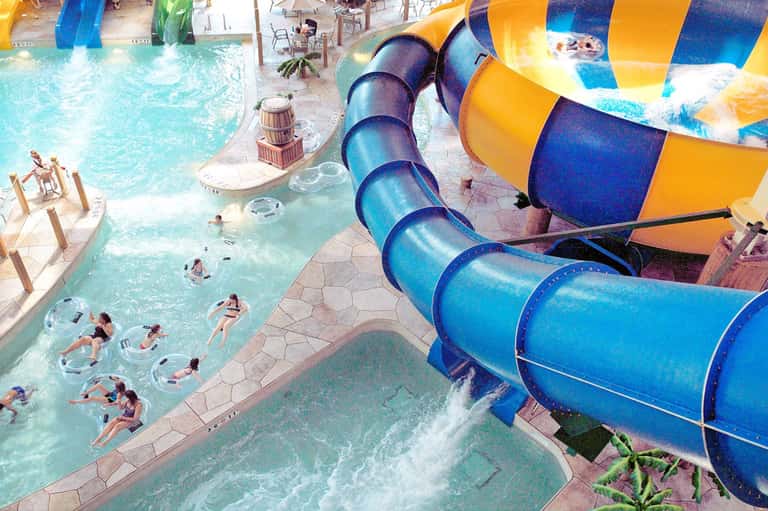 Aerial view of water park with blue slide, turquoise pools, and guests enjoying various attractions