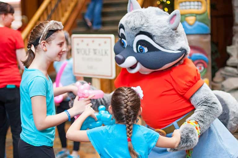 Children interacting with mascot character in red shirt at indoor entertainment venue