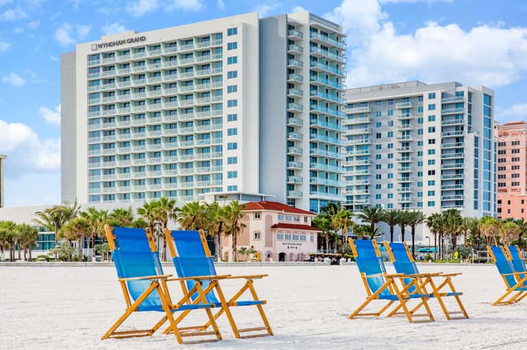 Wyndham Grand beachfront hotel with blue and yellow beach chairs on sandy shore