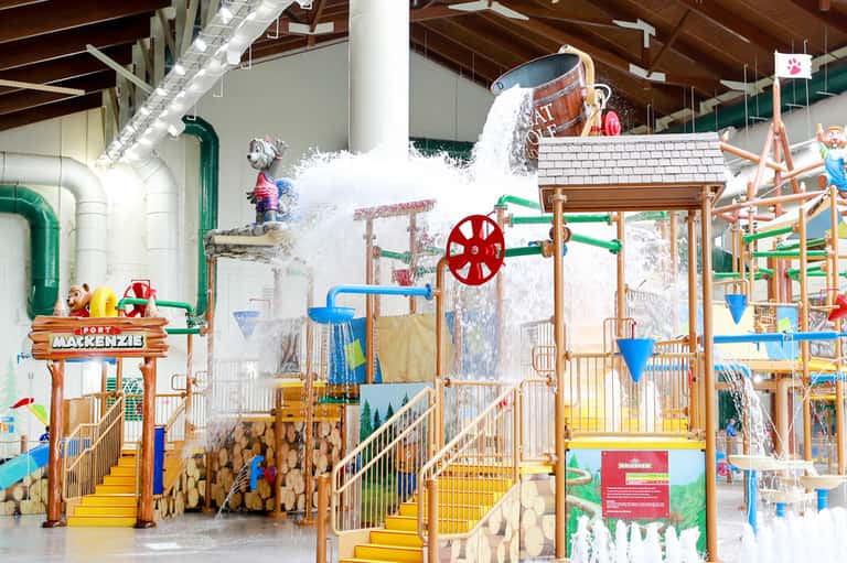 Indoor water park with Fort McKenzie theme, large water slide, wooden structures, and interactive water play features