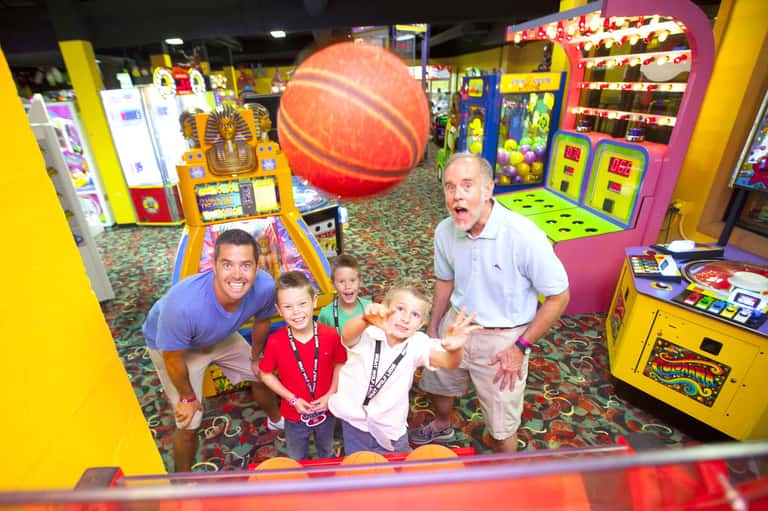 Family playing in colorful arcade with basketball game and ticket redemption machines