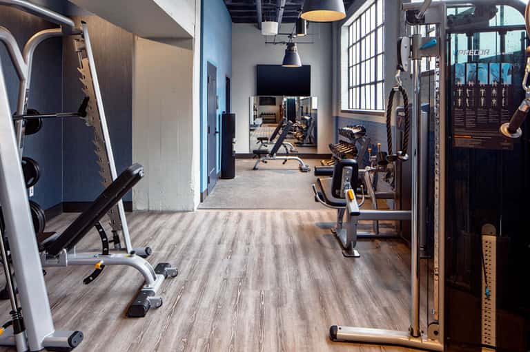 Modern fitness center with cardio equipment, weights, and gym machines on wood flooring