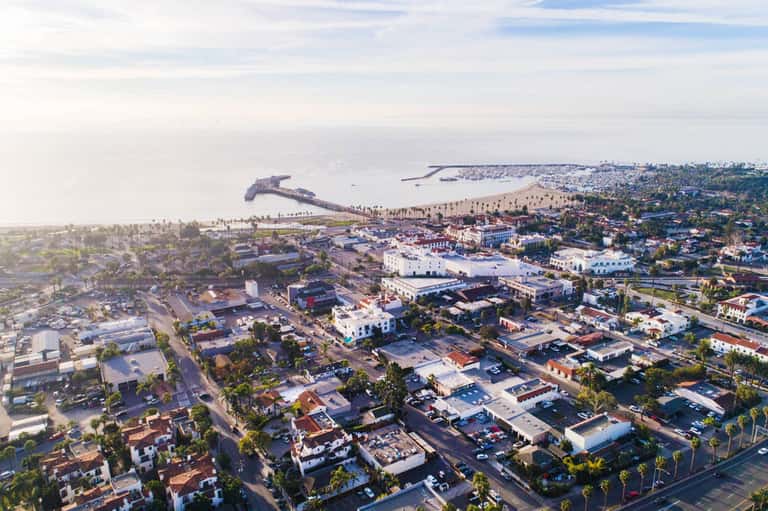 Aerial view of coastal resort town with ships, beach, palm trees, and residential buildings