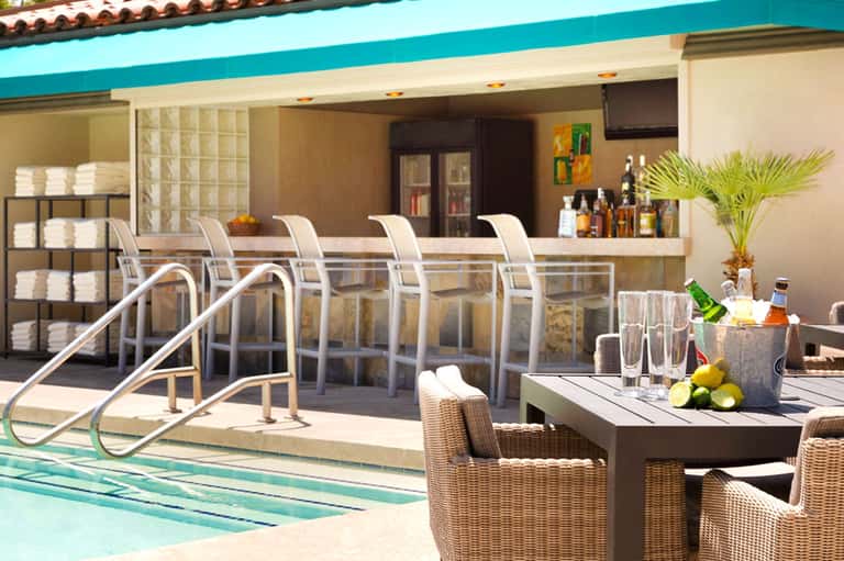 Pool bar area with white lounge chairs, turquoise bar counter, and tropical resort setting