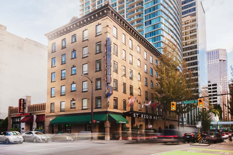 Historic St. Regis Hotel building facade on urban street corner with tall modern skyscrapers in background