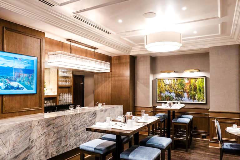 Upscale restaurant interior with marble bar, wood paneling, and elegant dining setup
