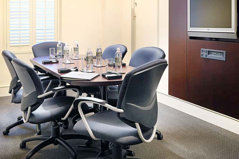 Professional conference room with oval table, ergonomic chairs, water bottles, and modern office setup