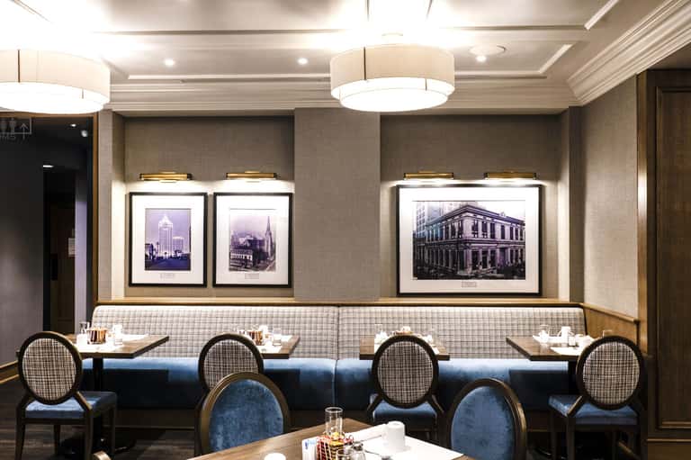Upscale dining room with framed architectural photographs, blue banquette seating, ambient lighting