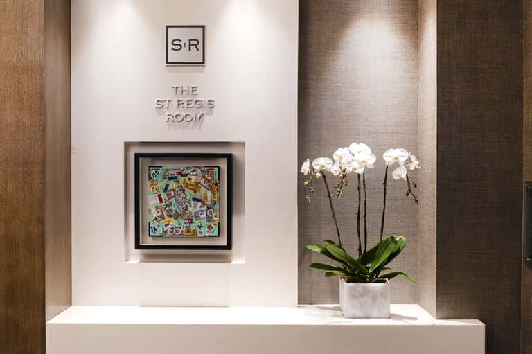 Elegant hallway entrance to St Regs Room with white orchids and modern wall art