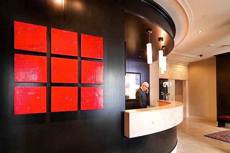 Modern hotel lobby with curved white reception desk, red wall art, and professional staff