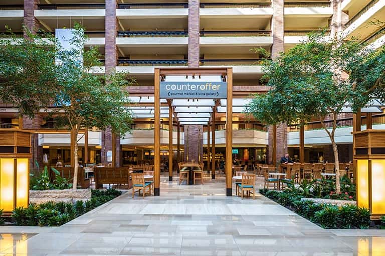 Indoor shopping mall with wooden beams, lush greenery, and Counteroffer storefront signage