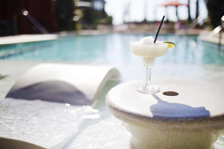 Frozen margarita cocktail with lime garnish on pool deck lounge chair