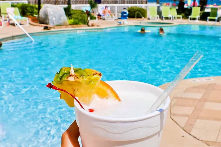 Tropical cocktail with pineapple garnish by poolside during daytime at resort