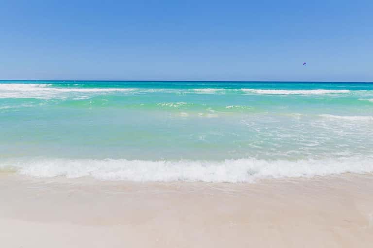 Pristine turquoise ocean with white sand beach and gentle waves under clear blue sky