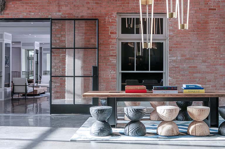 Exposed brick industrial space with wooden display table and sculptural wooden stools