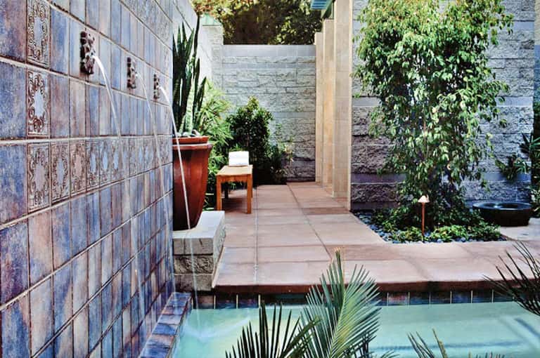 Modern courtyard pool with decorative blue tile walls and lush greenery
