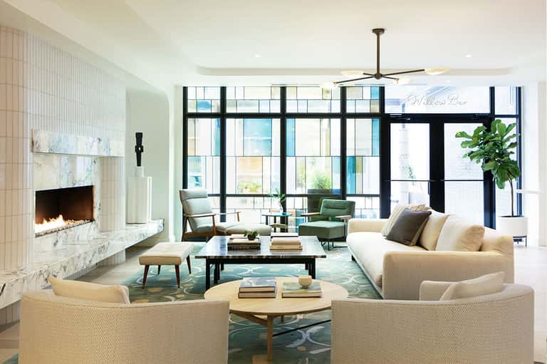 Contemporary living room with marble fireplace, large windows, beige seating, and ocean views