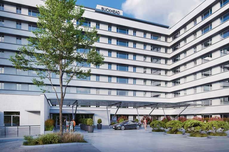 Modern Buckhead hotel courtyard with curved white building, landscaping, and covered entrance area