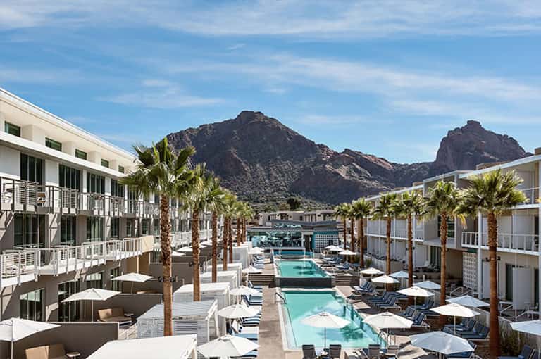 Modern resort with turquoise pools, palm trees, and mountain views in desert landscape