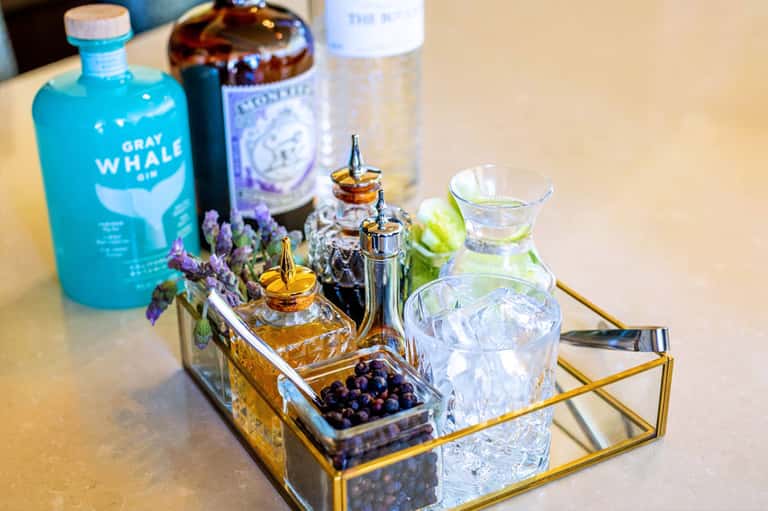Luxury cocktail display with bottles, perfume atomizers, purple flowers, and crystal glasses